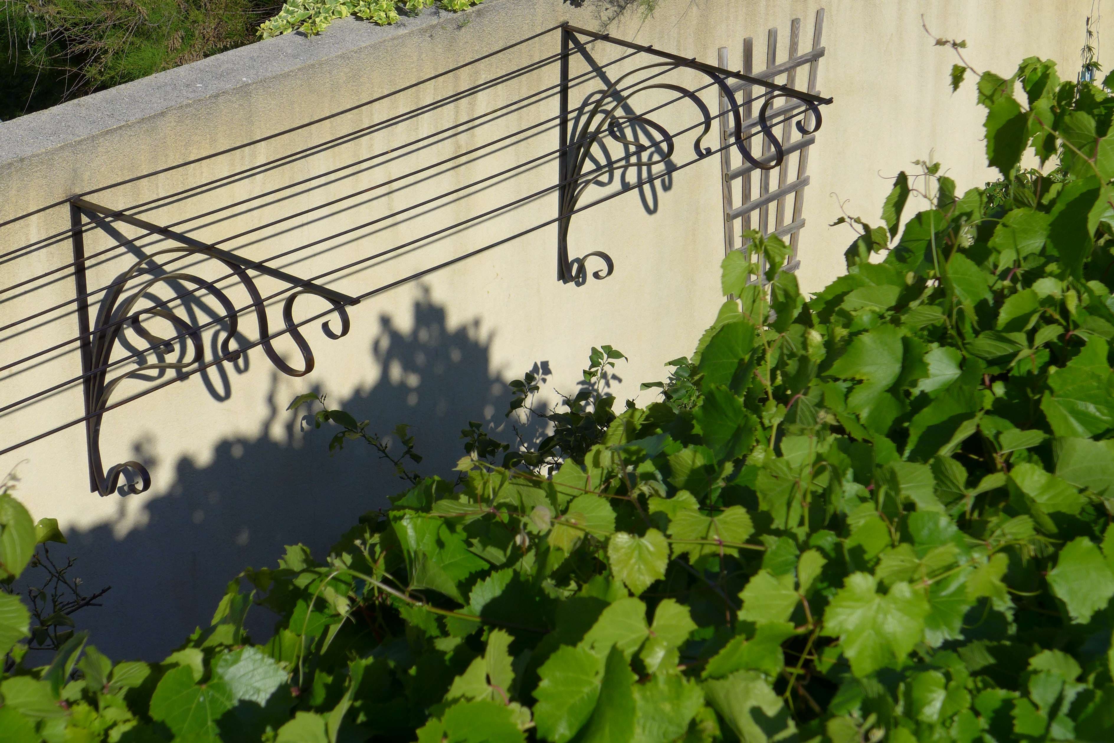 Marquise murale en fer forgé à volutes décoratives réalisée sur mesure par Ferronnerie Simon dans le Vaucluse